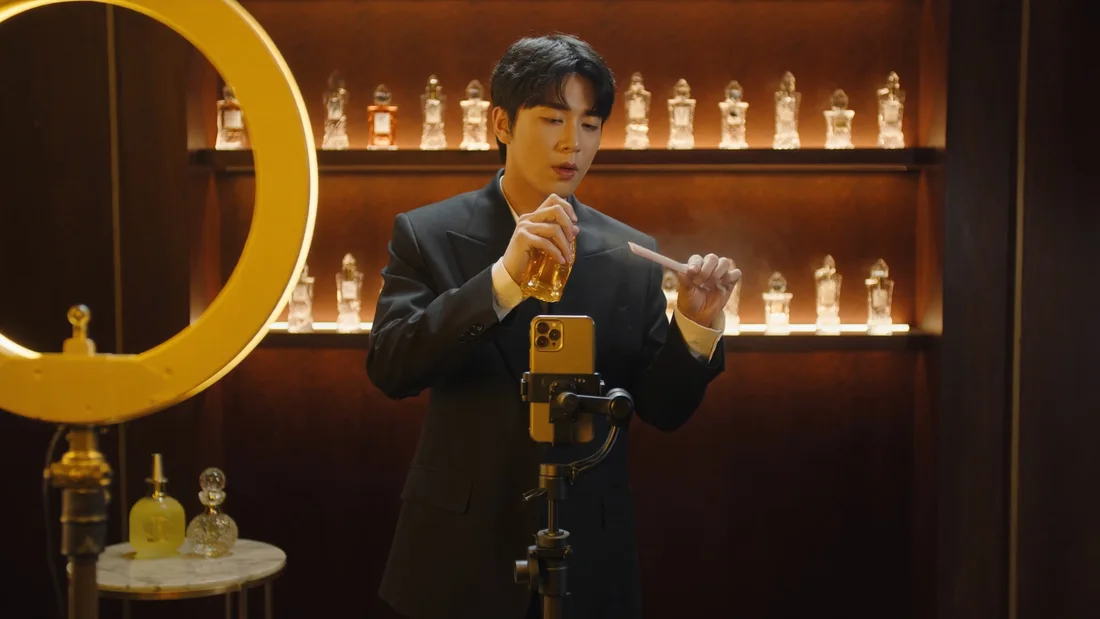Apresentador borrifa perfume em fita olfativa diante de smartphone vertical, no set de vídeos curtos
